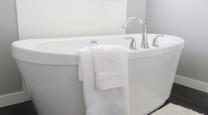 A white bathtub with a towel draped on it.